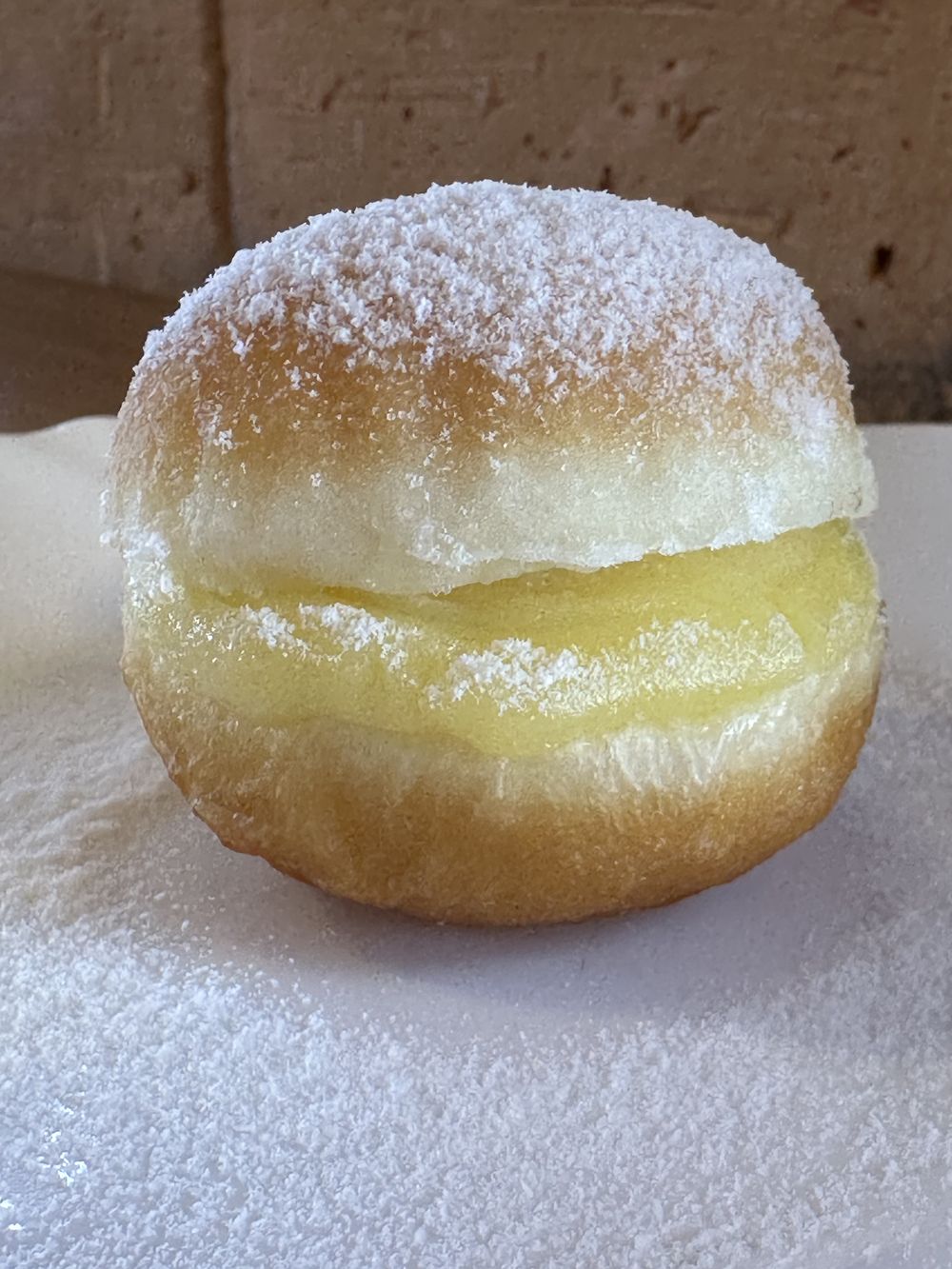 Sonho recheado com creme, coberto com açúcar de confeiteiro