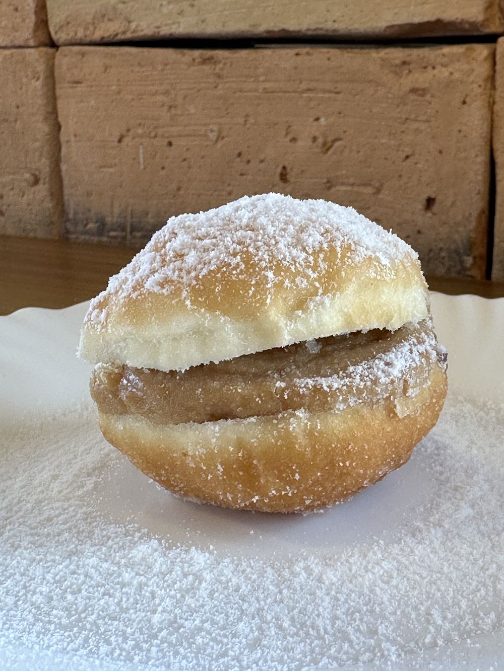 Sonho recheado com doce de leite, coberto com açúcar de confeiteiro